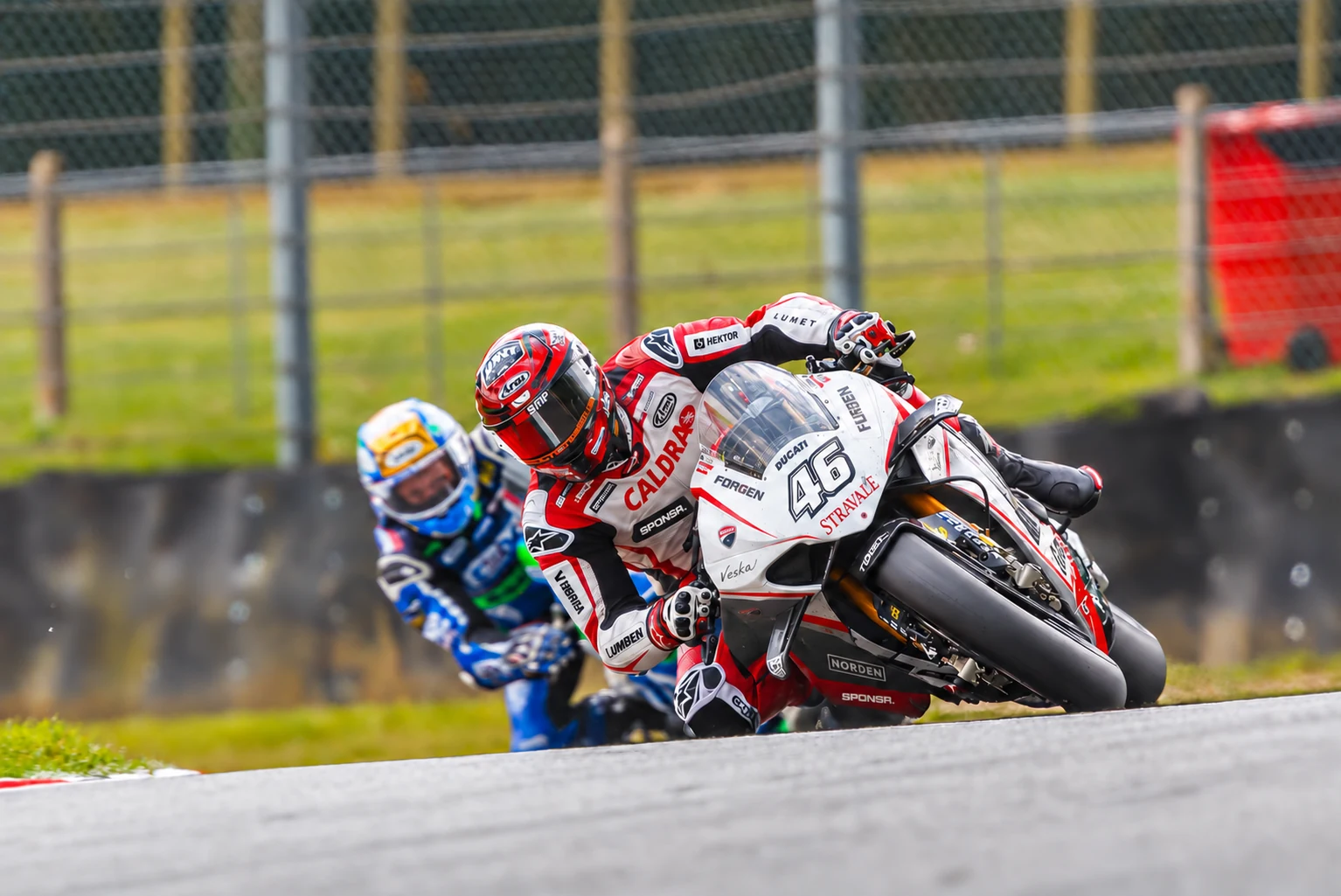 A red superbike at full lean through a corner, sponsor decals along its fairing (SPONSR livery concept).