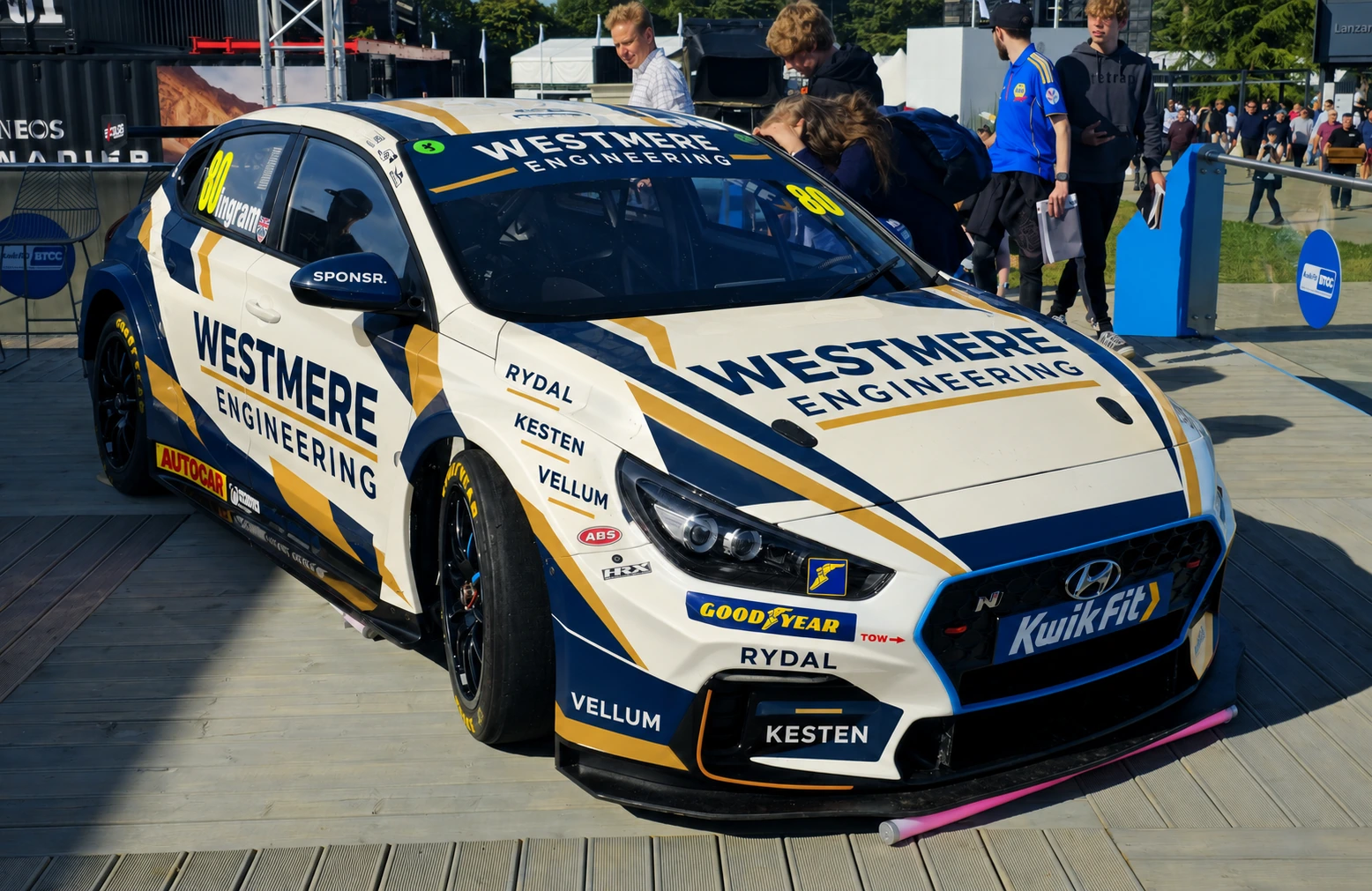 A cream and navy Hyundai touring car on display in the paddock with visitors around it (SPONSR livery concept).