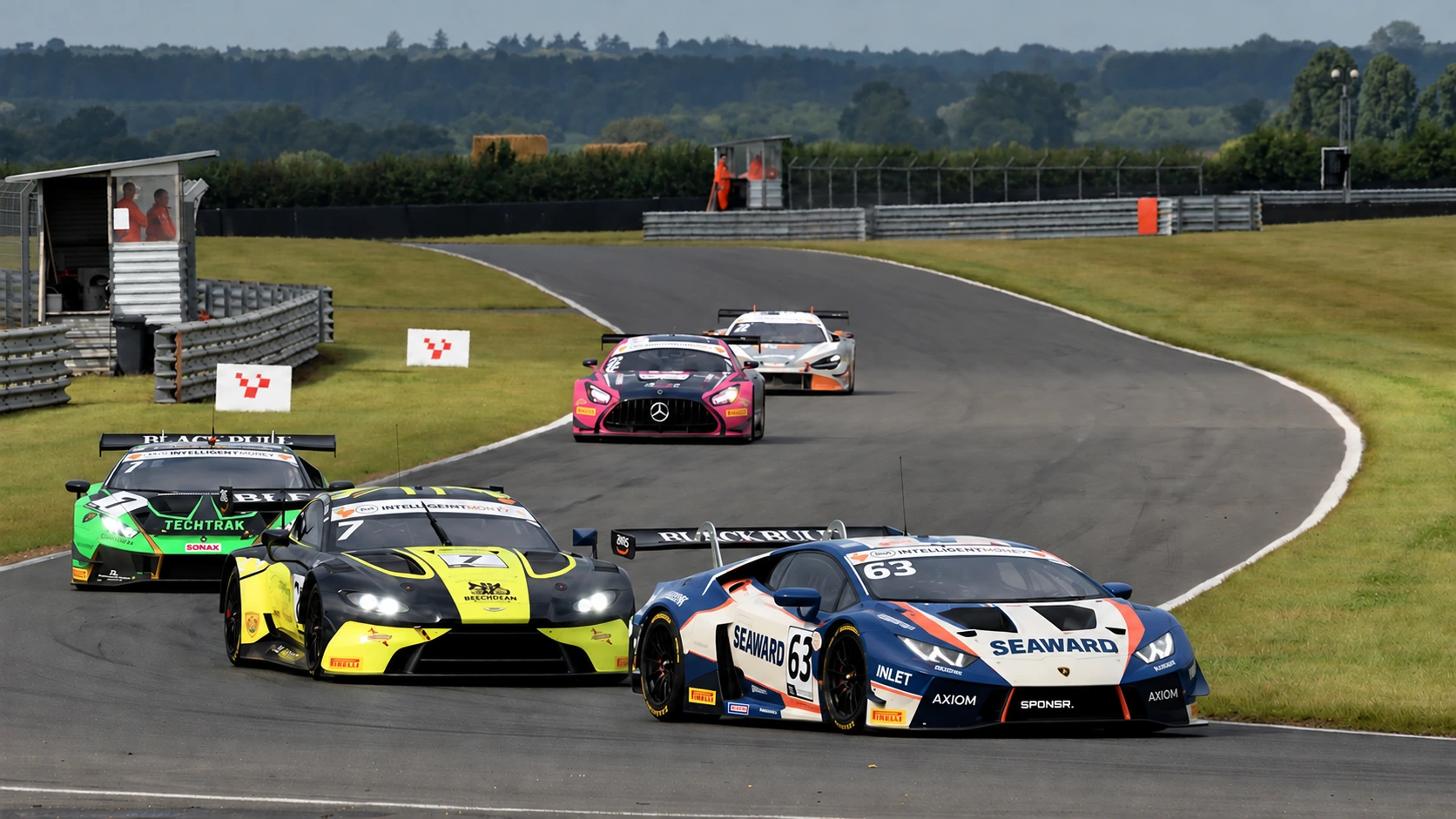 A train of GT cars led by a blue Lamborghini sweeping through a right-hander at Snetterton (SPONSR livery concept).